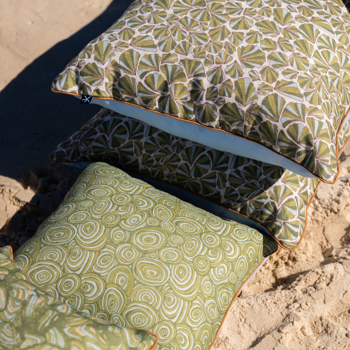 Growth Rings linen cushion styled with coordinating Shells cushions on the beach