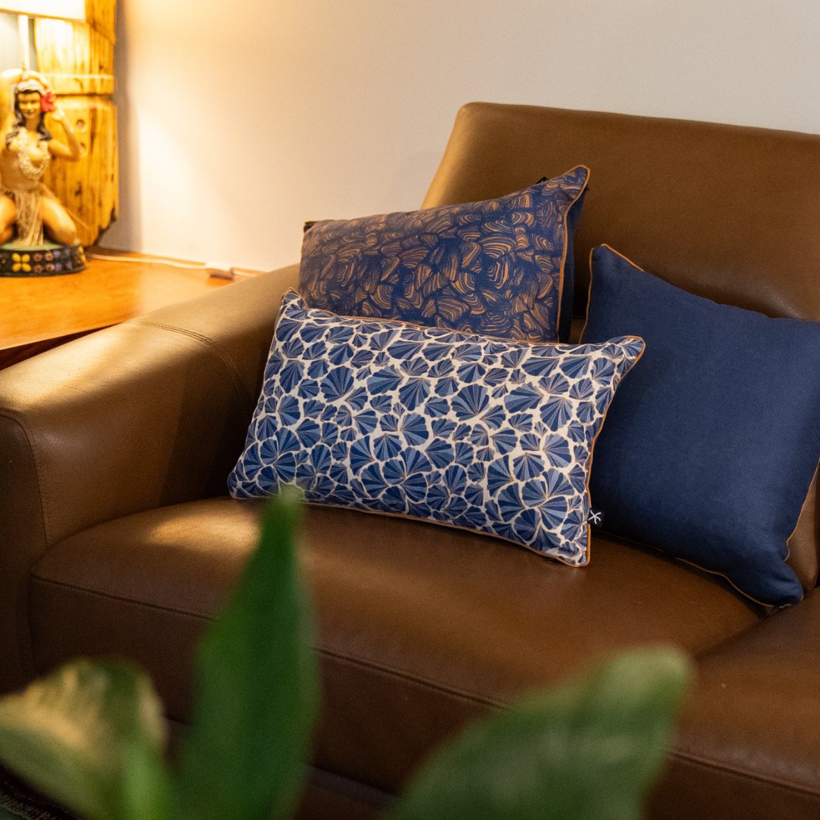 Mariner Shells lumbar linen cushion styled with coordinating blue cushions on a brown leather sofa