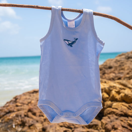 Pink tank top with a blue logo hanging on a branch against a rocky background