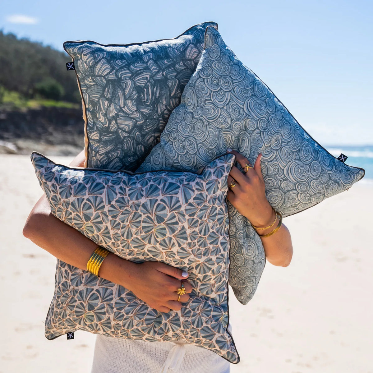 Frenchmans linen cushion collection in blue coastal prints styled on the beach.