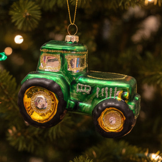 Glass tractor Christmas ornament on Christmas tree.