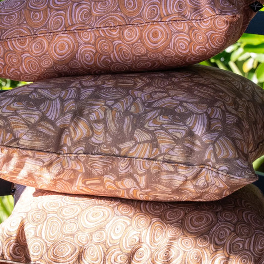 Close-up of Claytons colourway outdoor cushions featuring the Growth Rings and Pipi patterns in warm earthy tones.
