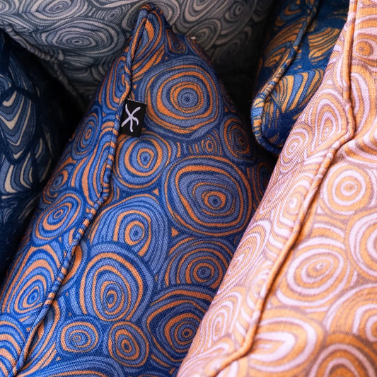 Close-up detail of a Mariner colourway Growth Rings cushion layered with coordinating Starfish Studio cushions.