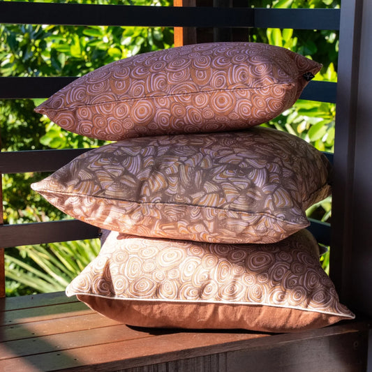 Outdoor indoor cushion covers in the Claytons colourway, including Growth Rings and Pipi prints, stacked on an outdoor bench.