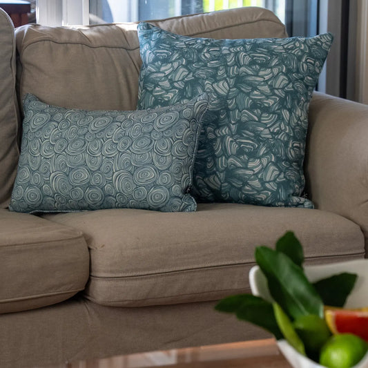 Outdoor Indoor Growth Rings cushion cover in Frenchman paired with a teal swirl print cushion on a sofa by a window