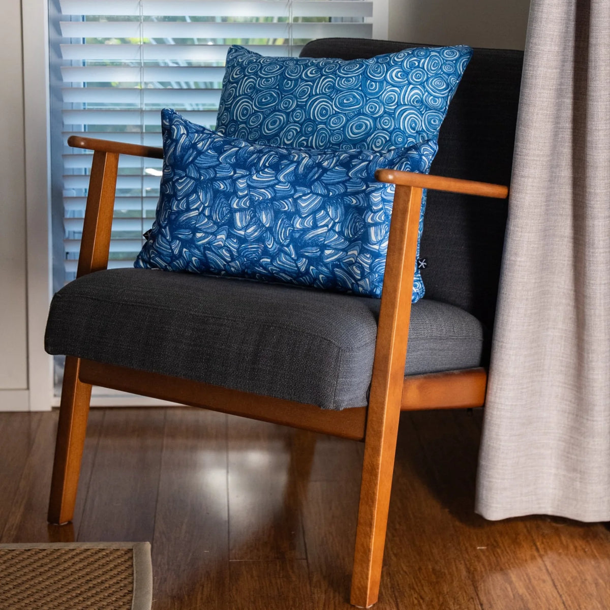 Ocean Growth Rings outdoor indoor cushion cover styled with a coordinating blue print cushion on a black woven chair.